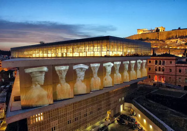 Il museo dell'Acropoli dall'esterno di sera con il Partenone sullo sfondo.