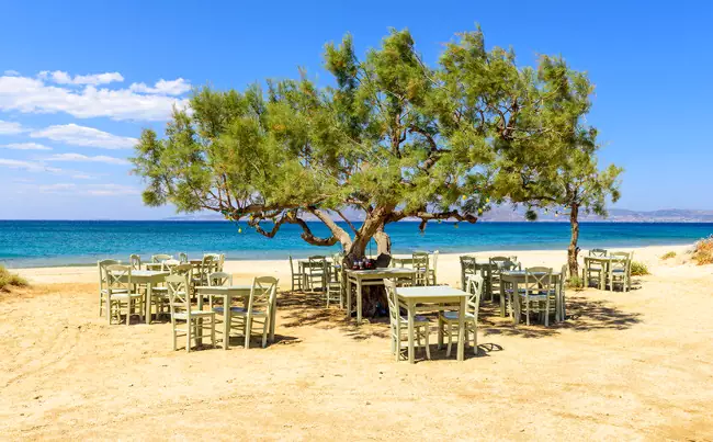 La meravigliosa spiaggia di Plaka, con i tavoli di una taverna per mangiare al mare.