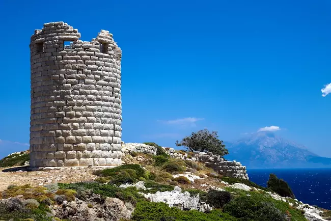 La torre di Drakano sull'isola greca di Ikaria e sullo sfondo le montagne di Samos dopo il mare.